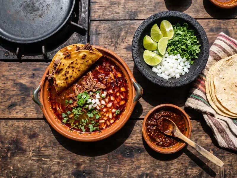 Birria de Res — shot from directly overhead: beef braised in a deep red chilli broth until it shreds