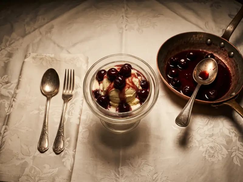 Cherries Jubilee — shot from directly overhead: cherries in a light syrup flamed with kirsch and spooned burning over vanilla ice cream