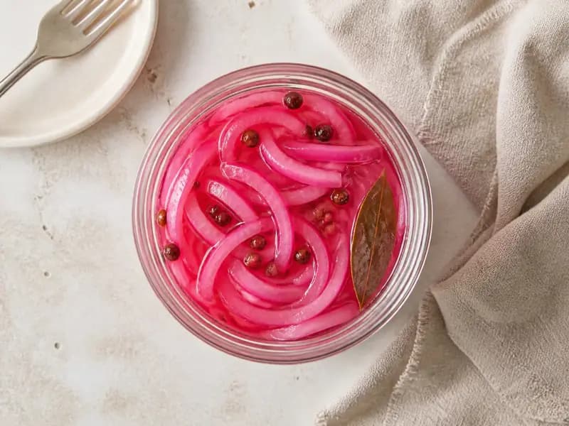 Quick Pickled Red Onions — shot from directly overhead: thin red onion slices covered in warm sweet-sharp brine